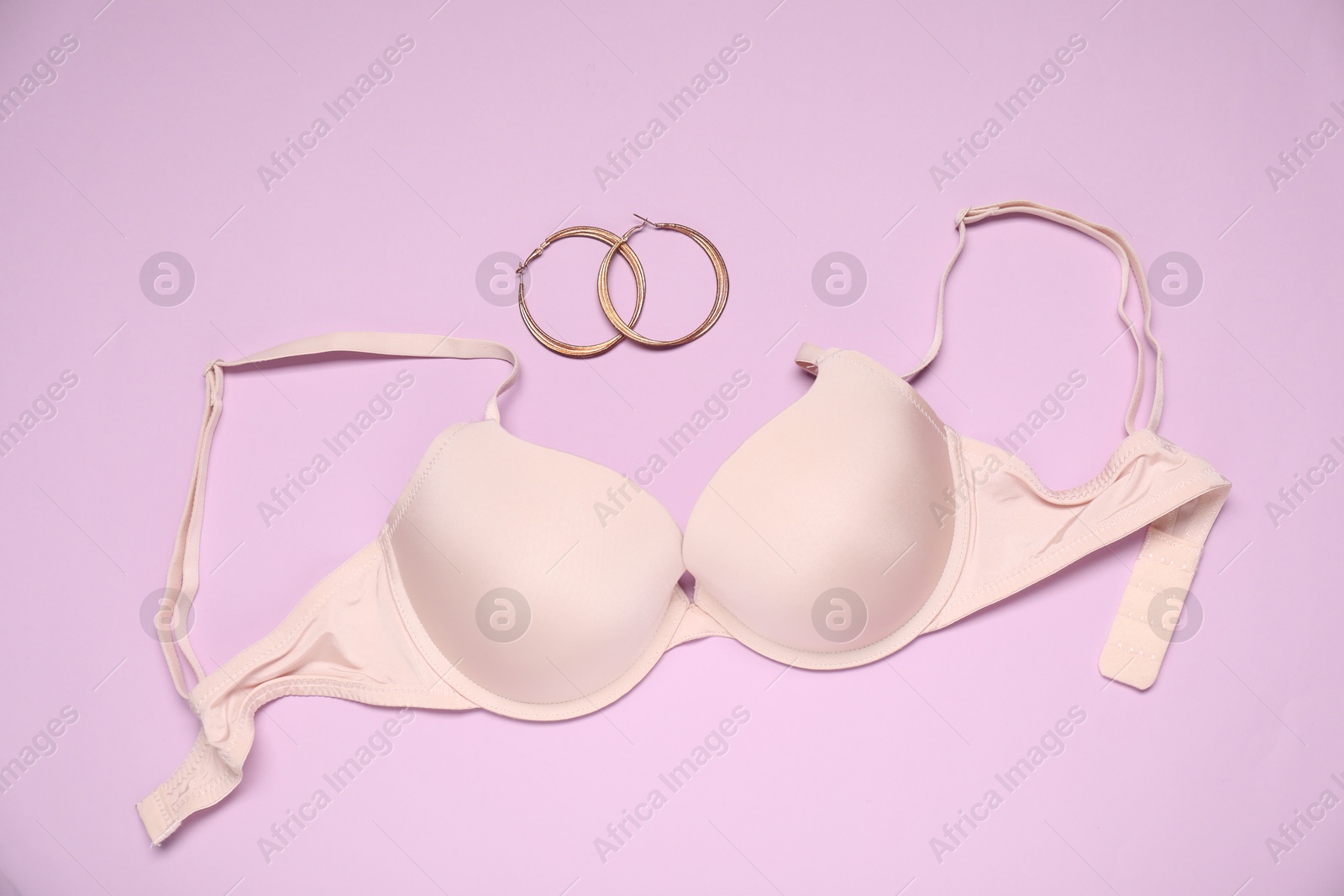 Beautiful bra and earrings on beige background, flat lay Photo of Beautiful bra and earrings on beige background, flat lay