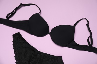 Photo of Beautiful black bra and panties on pink background, flat lay