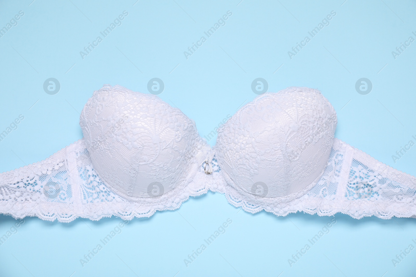 Beautiful white lace bra on light blue background, top view Photo of Beautiful white lace bra on light blue background, top view
