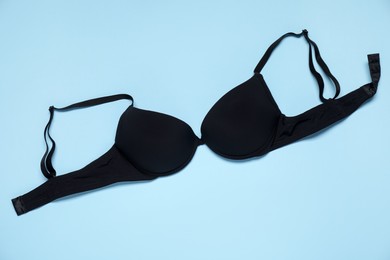 Photo of Beautiful black bra on light blue background, top view