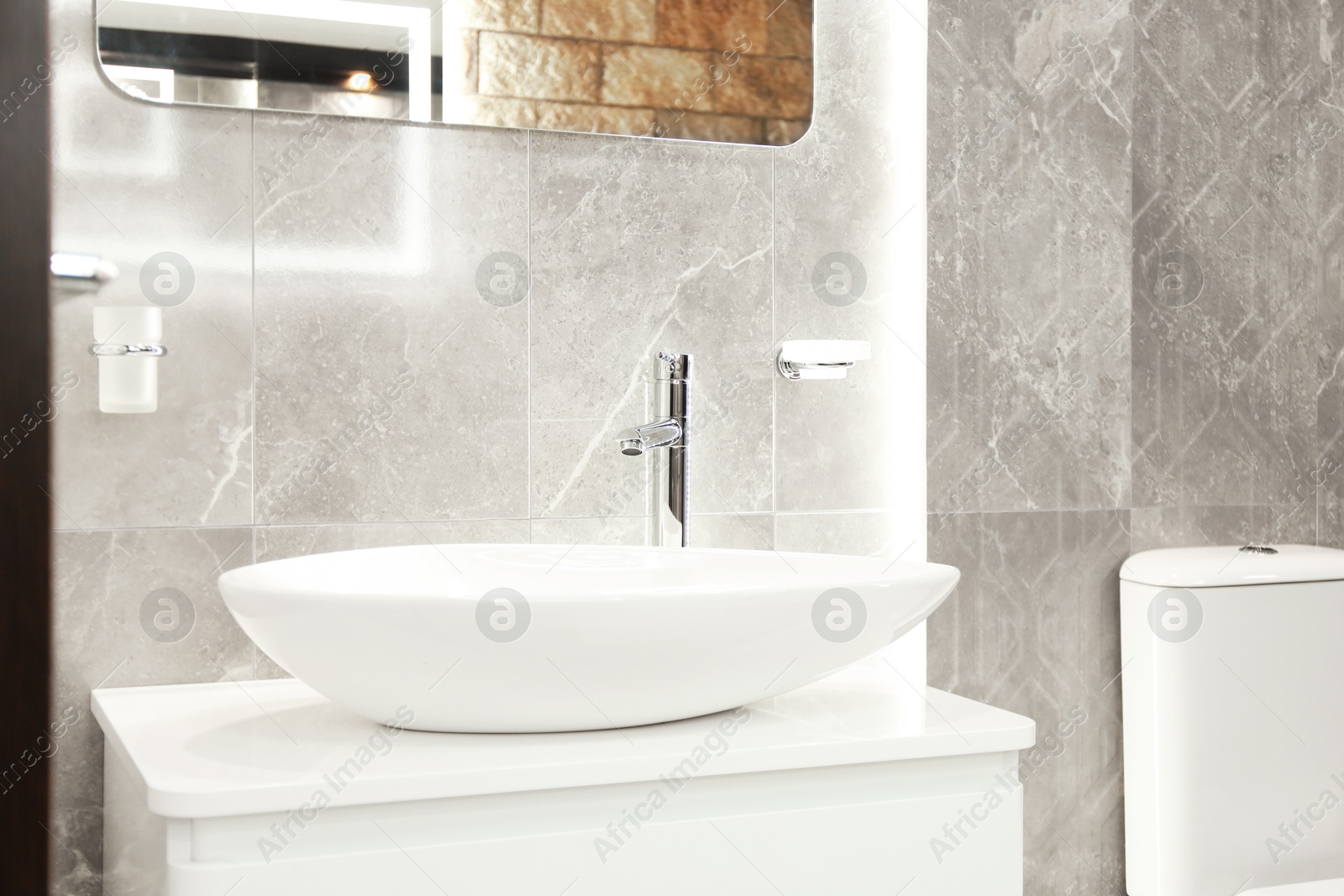 Stylish bathroom with vessel sink and vanity near tiled wall. Interior design Photo of Stylish bathroom with vessel sink and vanity near tiled wall. Interior design