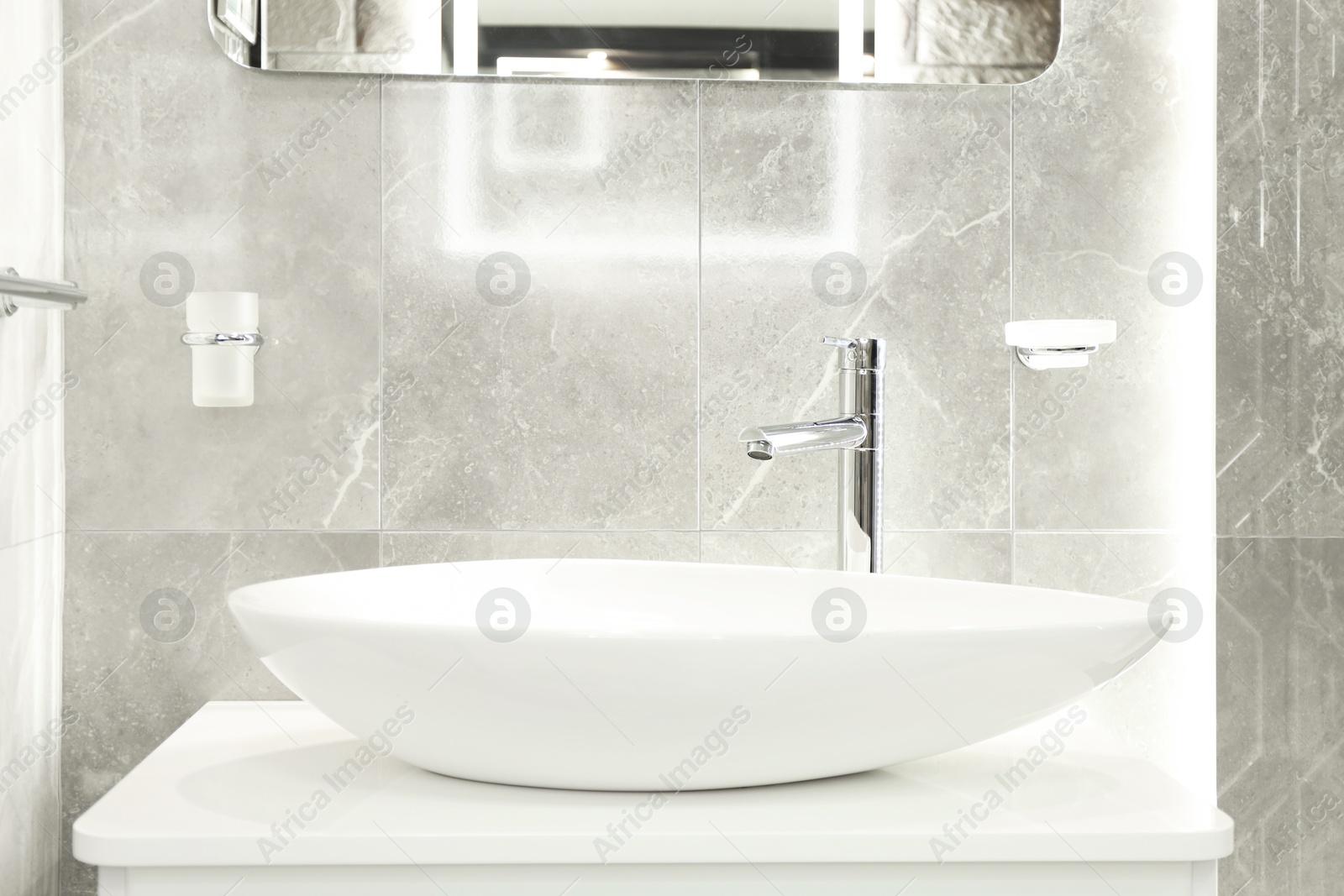 Stylish bathroom with vessel sink and vanity near tiled wall. Interior design Photo of Stylish bathroom with vessel sink and vanity near tiled wall. Interior design