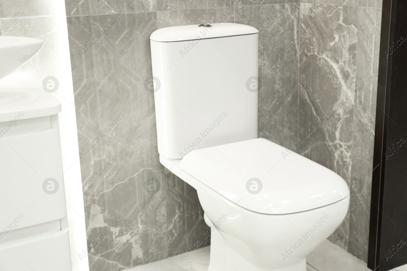 Stylish bathroom with toilet bowl near tiled wall. Interior design Photo of Stylish bathroom with toilet bowl near tiled wall. Interior design