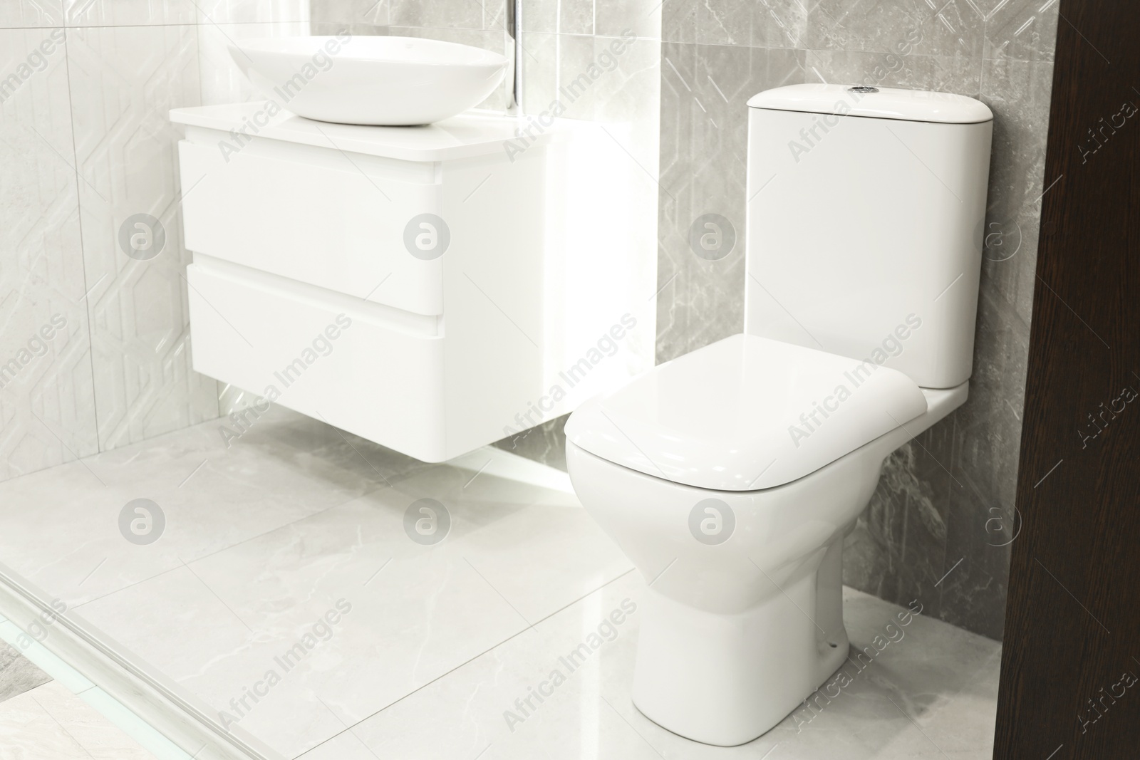 Stylish bathroom with vanity and toilet bowl near tiled wall. Interior design Photo of Stylish bathroom with vanity and toilet bowl near tiled wall. Interior design