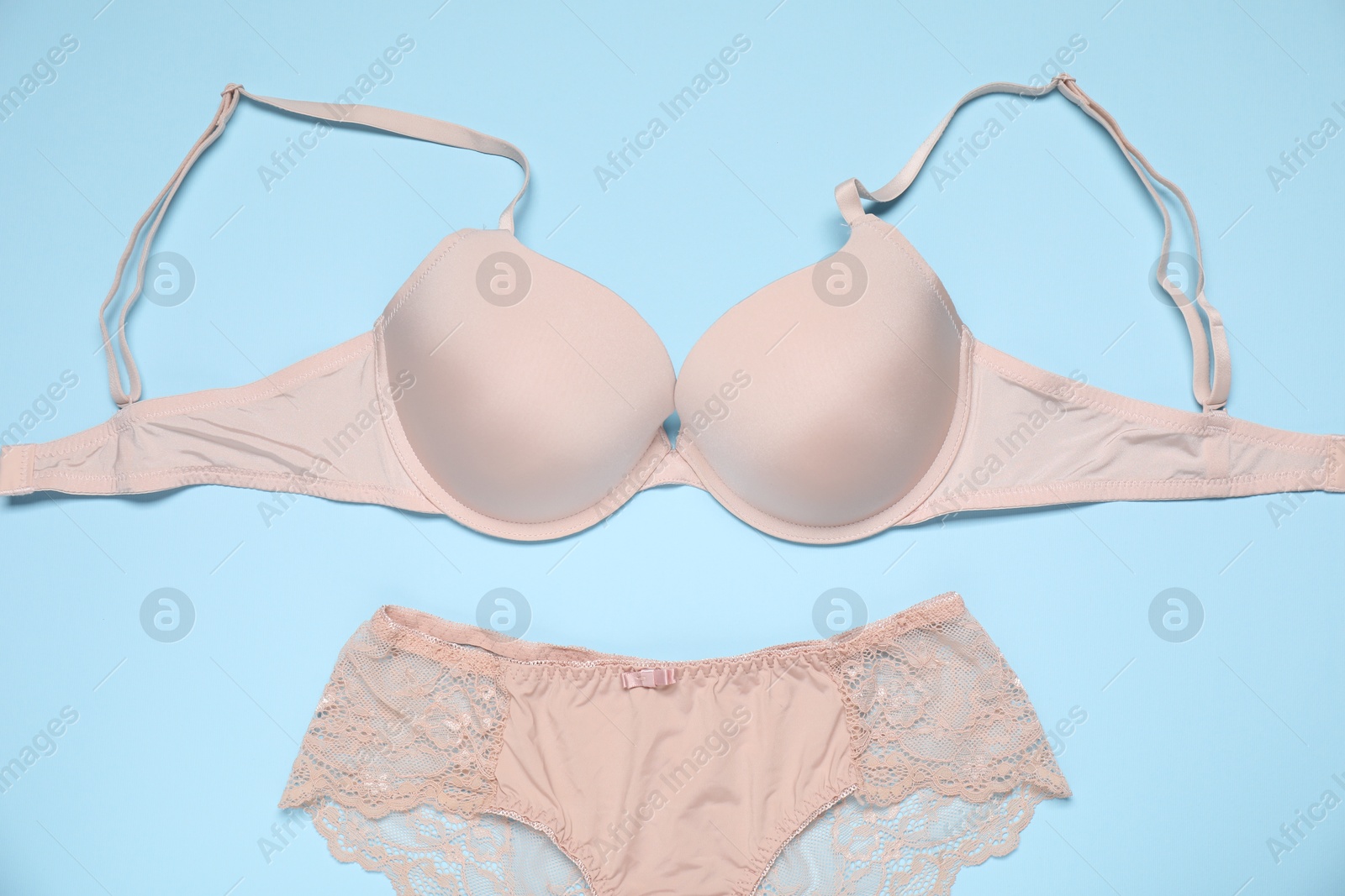 Beautiful beige bra and panties on light blue background, flat lay Photo of Beautiful beige bra and panties on light blue background, flat lay