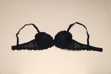 Photo of One black lace bra on beige background, top view