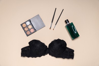 Photo of Flat lay composition with black lace bra and cosmetic products on beige background