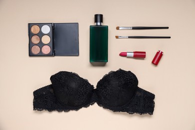Photo of Flat lay composition with black lace bra and cosmetic products on beige background