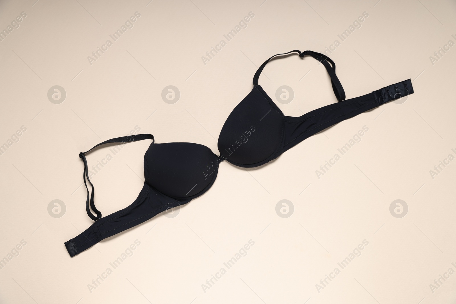 One black bra on beige background, top view Photo of One black bra on beige background, top view