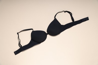 Photo of One black bra on beige background, top view