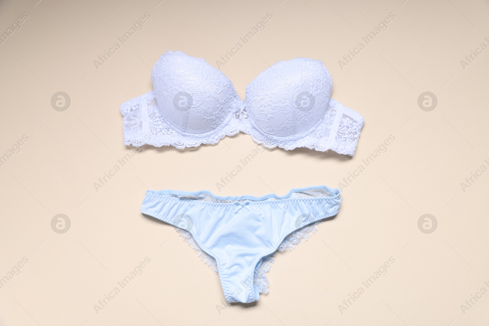 Photo of White lace bra and panties on beige background, flat lay