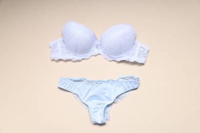 Photo of White lace bra and panties on beige background, flat lay