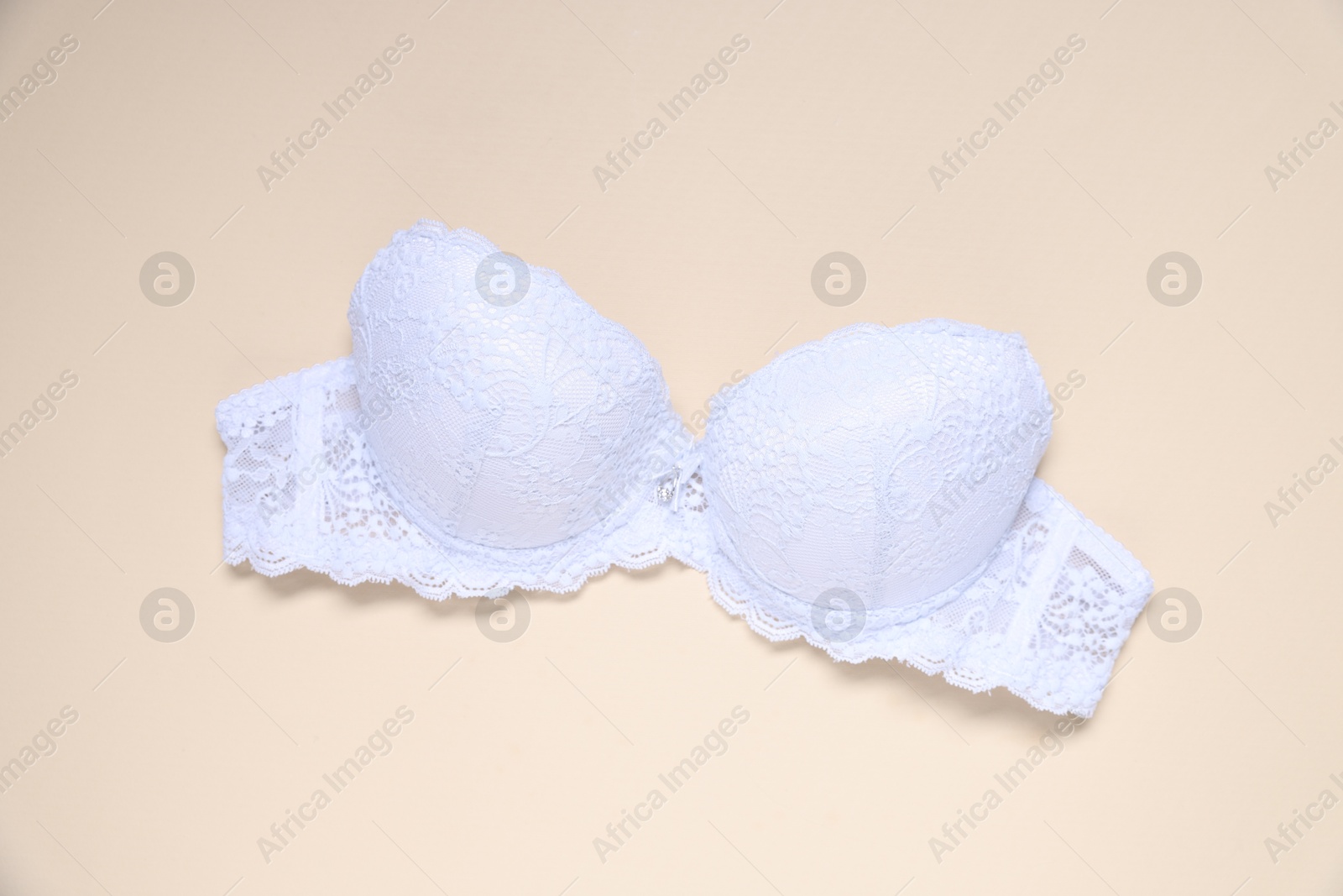 One white lace bra on beige background, top view Photo of One white lace bra on beige background, top view