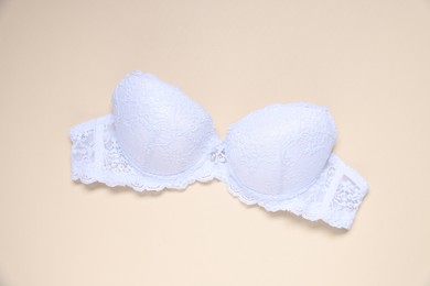 Photo of One white lace bra on beige background, top view