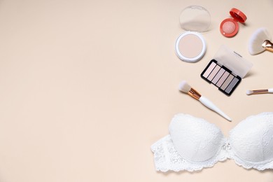 Photo of Flat lay composition with white lace bra and cosmetic products on beige background. Space for text
