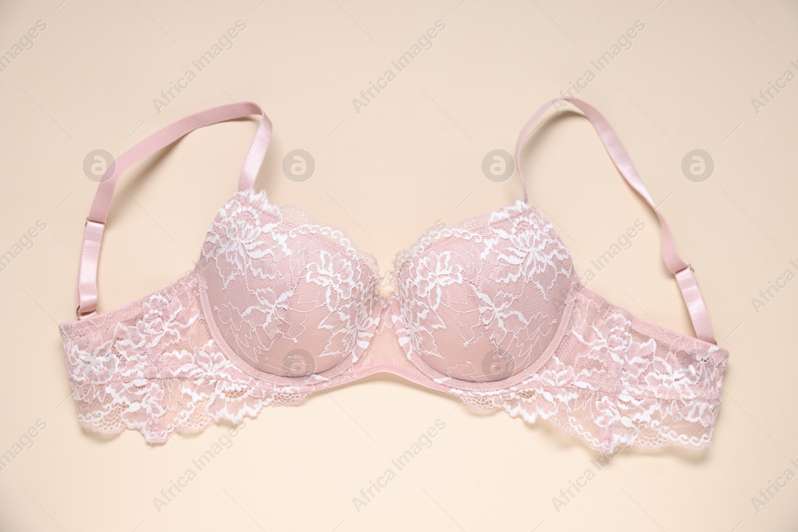 One pink lace bra on beige background, top view Photo of One pink lace bra on beige background, top view