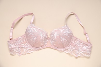 Photo of One pink lace bra on beige background, top view