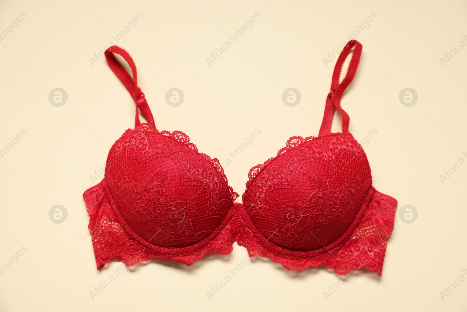 One red lace bra on beige background, top view Photo of One red lace bra on beige background, top view