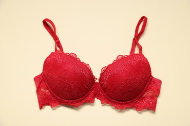 Photo of One red lace bra on beige background, top view