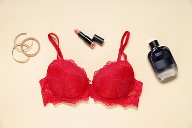 Photo of Flat lay composition with red lace bra and cosmetic products on beige background