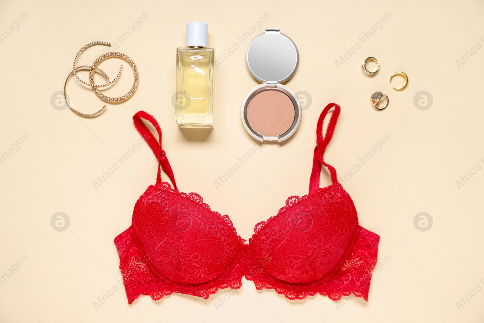 Flat lay composition with red lace bra and cosmetic products on beige background Photo of Flat lay composition with red lace bra and cosmetic products on beige background