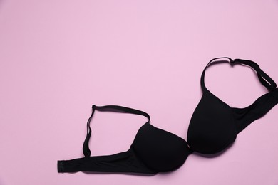 Photo of One black bra on pink background, top view. Space for text