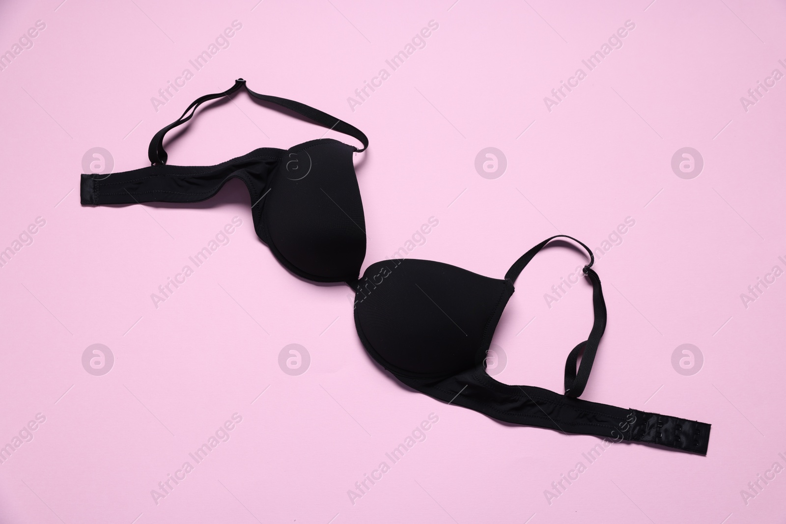 Photo of One black bra on pink background, top view