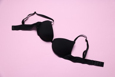 Photo of One black bra on pink background, top view