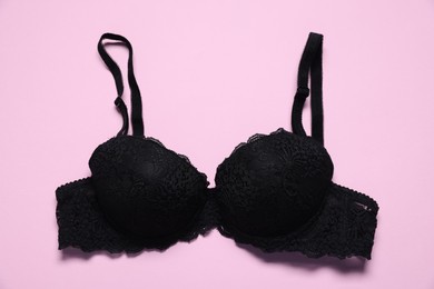 Photo of One black lace bra on pink background, top view