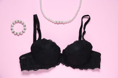 Photo of Black lace bra and jewelry on pink background, flat lay