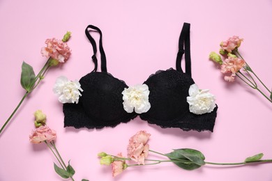 Photo of Black bra and eustoma flowers on pink background, flat lay