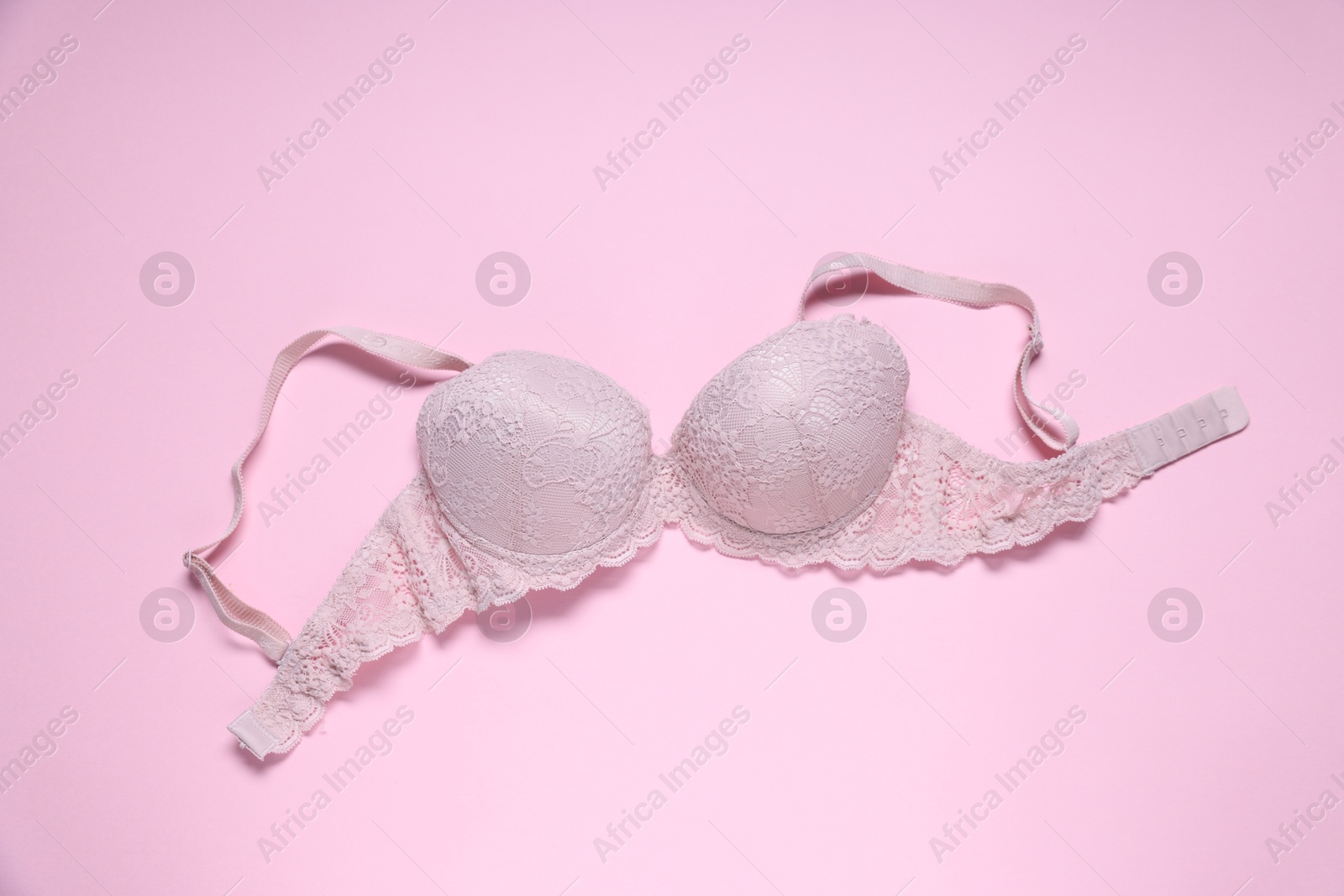 Photo of One lace bra on pink background, top view