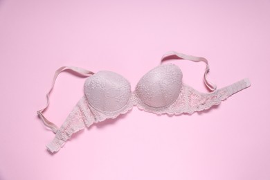 Photo of One lace bra on pink background, top view