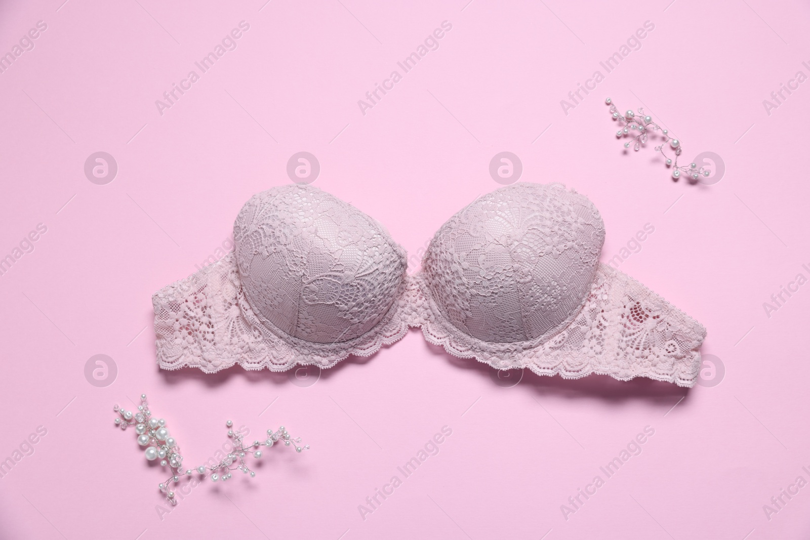 Photo of Lace bra and decorative elements on pink background, flat lay