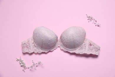 Photo of Lace bra and decorative elements on pink background, flat lay