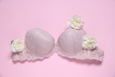 Photo of Lace bra and eustoma flowers on pink background, top view