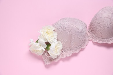 Photo of Lace bra and eustoma flowers on pink background, top view