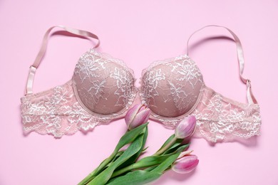 Photo of Lace bra and tulip flowers on pink background, flat lay
