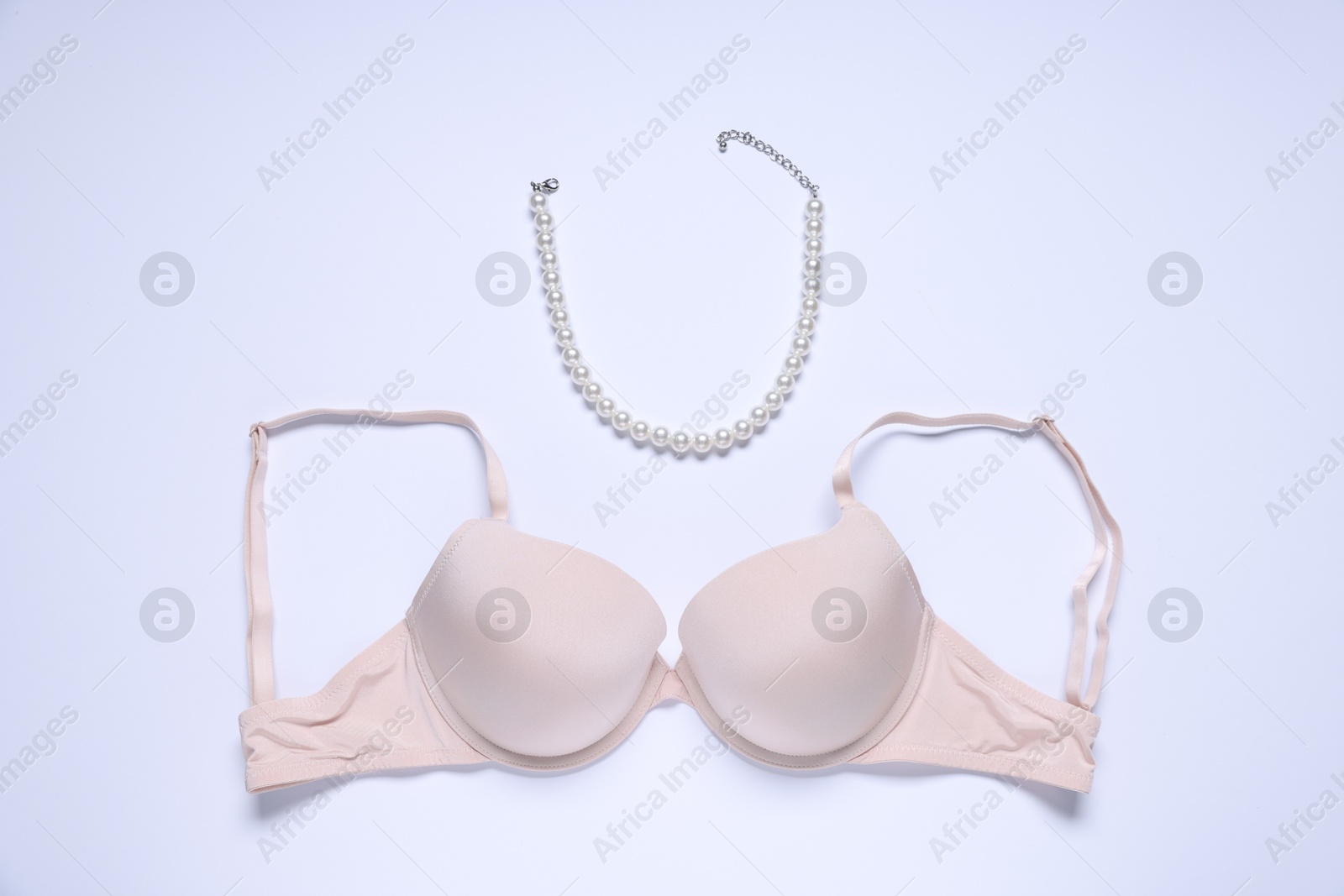 Photo of Pink bra and necklace on white background, flat lay