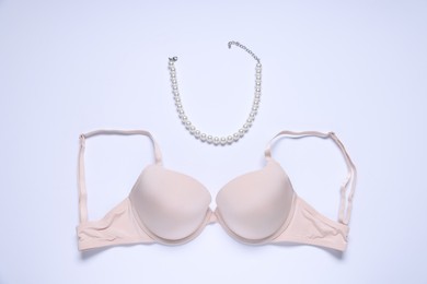 Photo of Pink bra and necklace on white background, flat lay