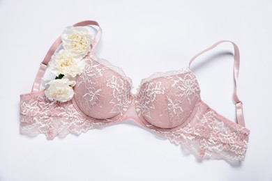 Photo of Pink lace bra and eustoma flowers on white background, top view