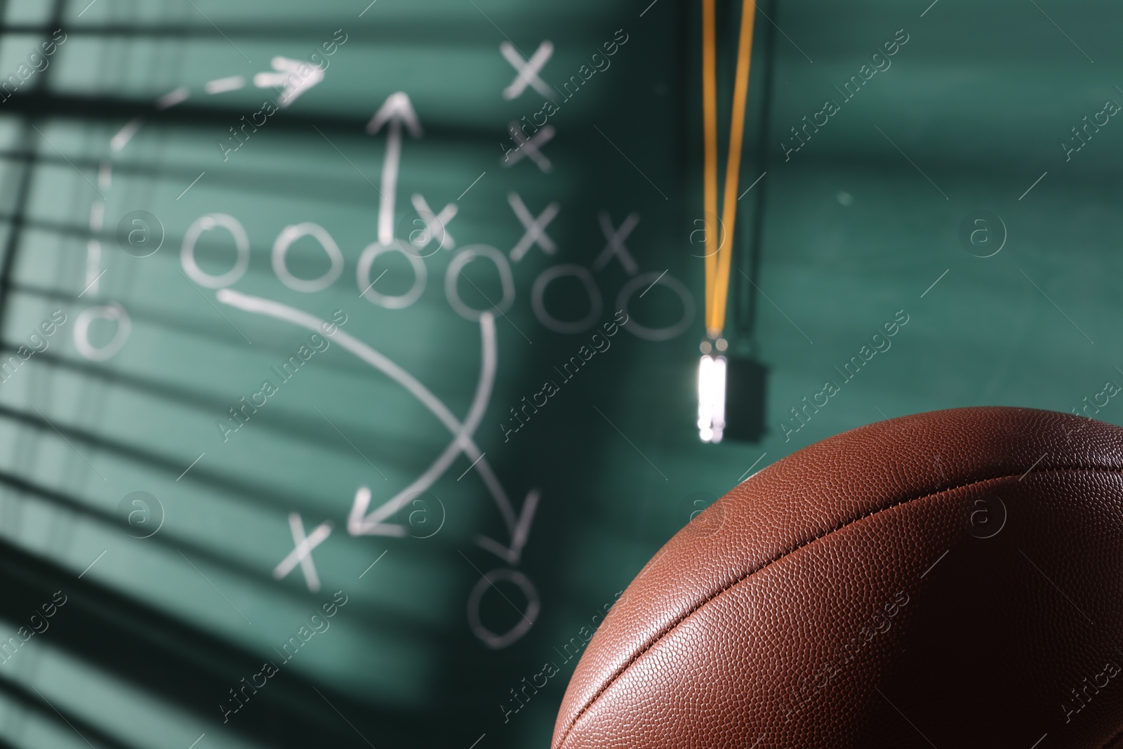 American football ball near chalkboard with scheme of game, closeup Photo of American football ball near chalkboard with scheme of game, closeup