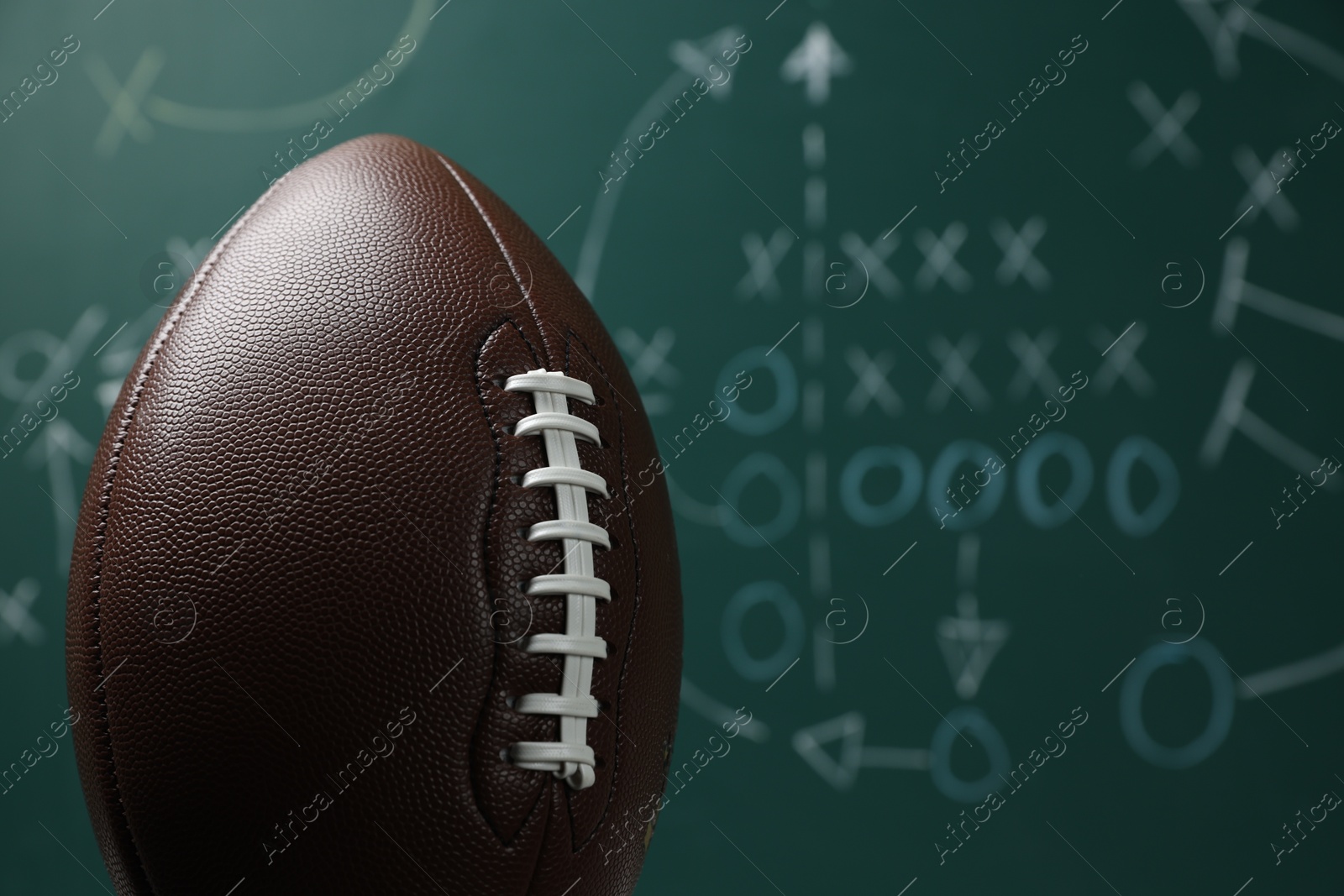 American football ball against blurred game scheme, closeup Photo of American football ball against blurred game scheme, closeup