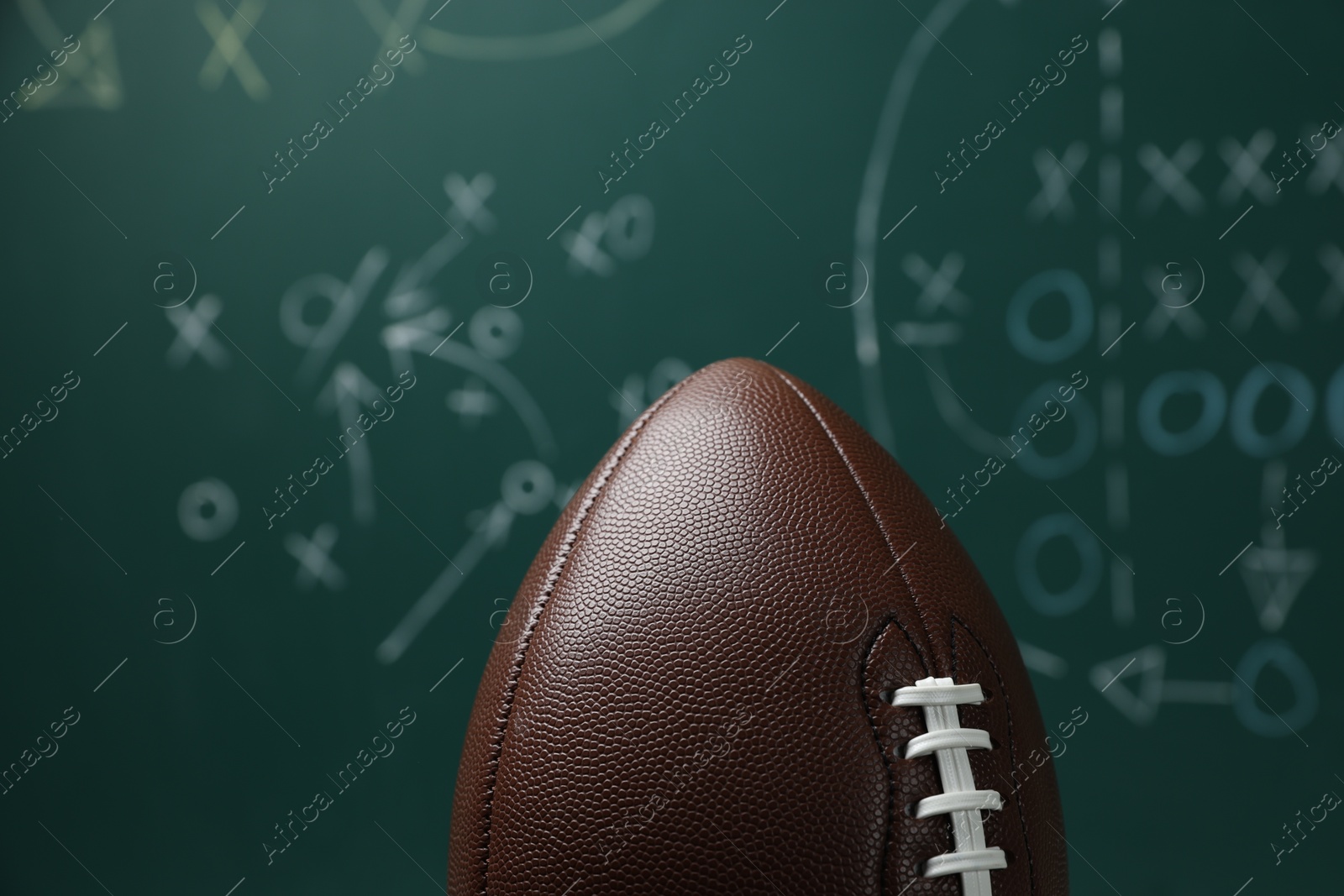 American football ball against blurred game scheme, closeup Photo of American football ball against blurred game scheme, closeup