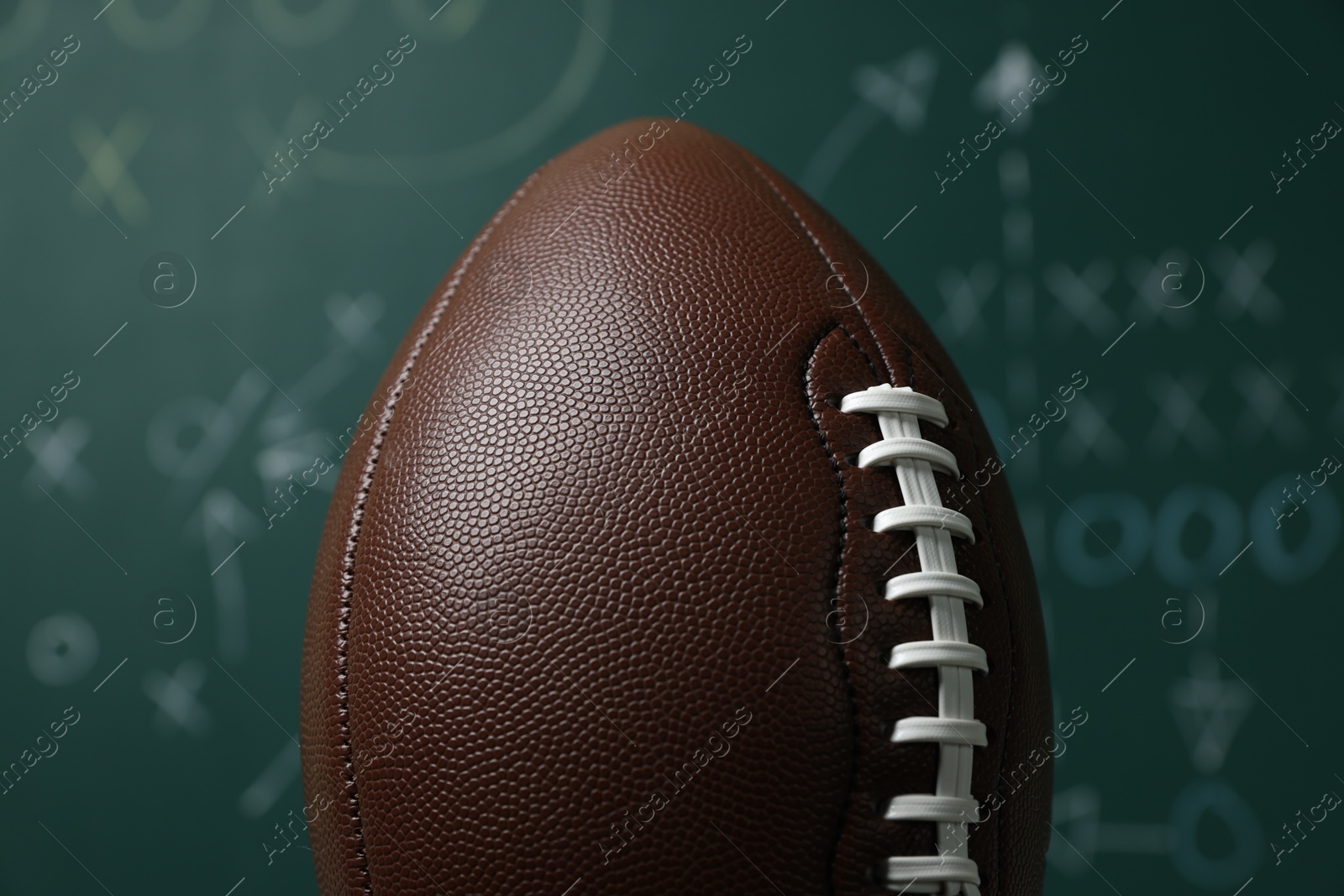 American football ball against blurred game scheme, closeup Photo of American football ball against blurred game scheme, closeup