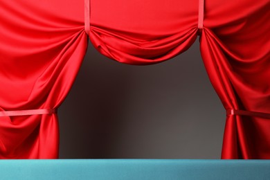 Photo of Puppet show. Empty light blue stage with red curtains against grey background