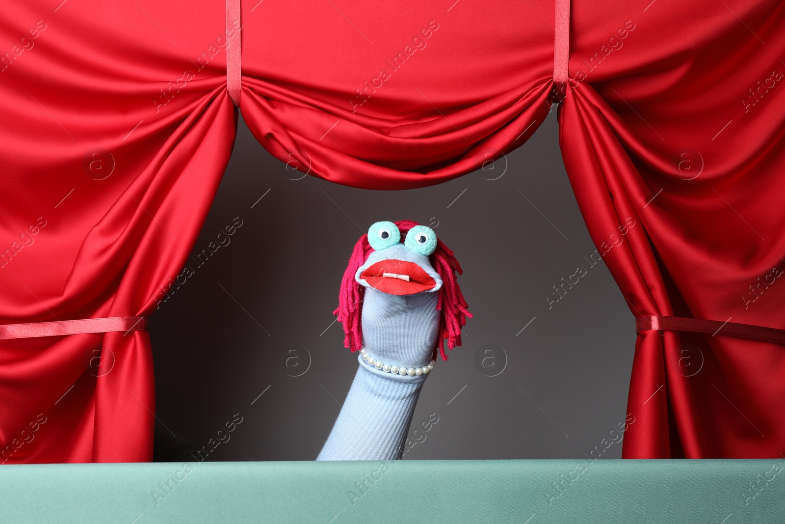 Photo of Creative puppet show on stage with red curtains