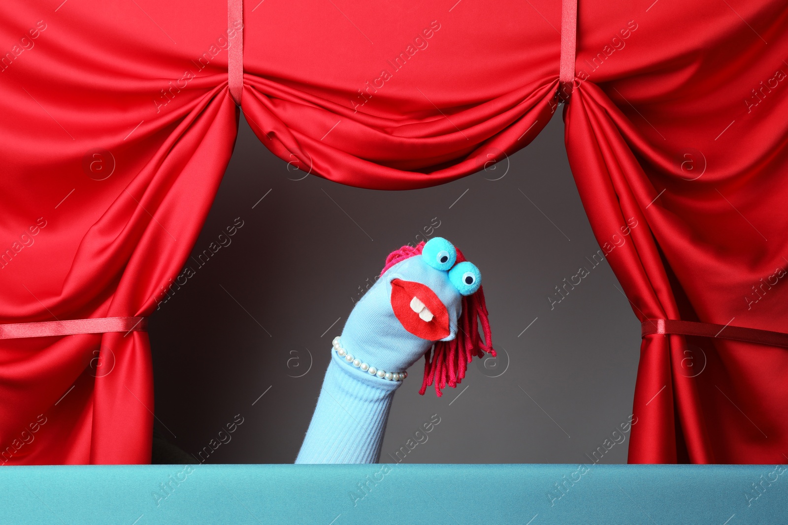 Photo of Creative puppet show on stage with red curtains