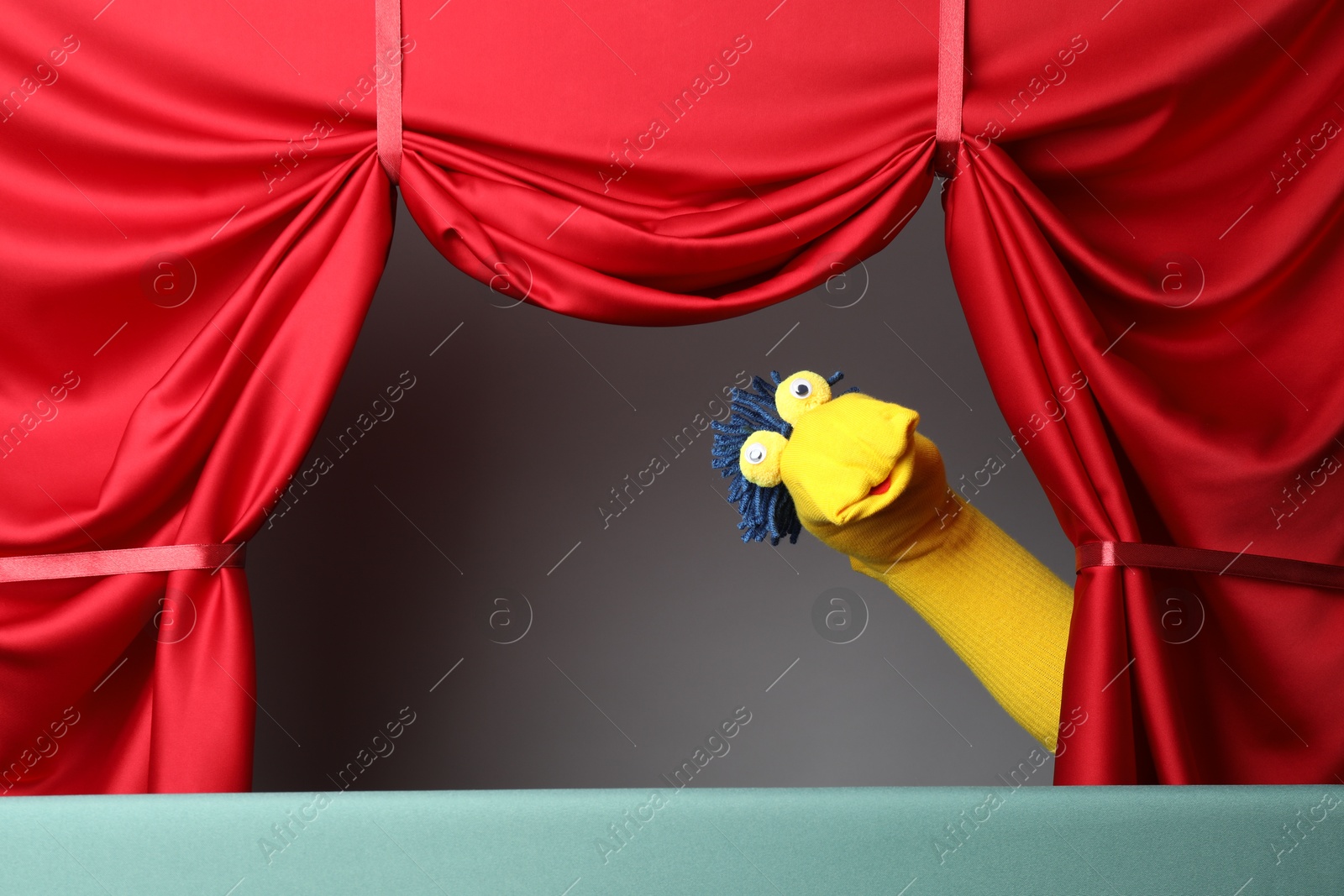 Photo of Creative puppet show on stage with red curtains