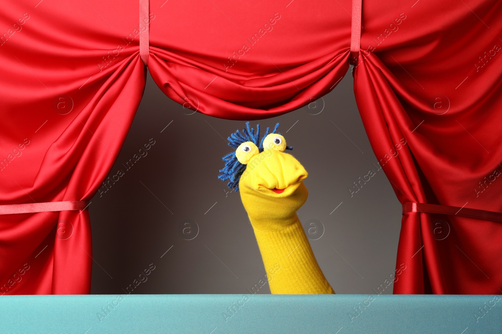 Photo of Creative puppet show on stage with red curtains